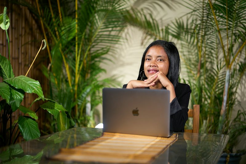 A woman working on her laptop among tropical plants