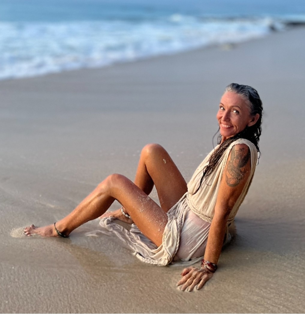 Magdalena, founder of Dharma Shakti, sitting on the shore at sunrise