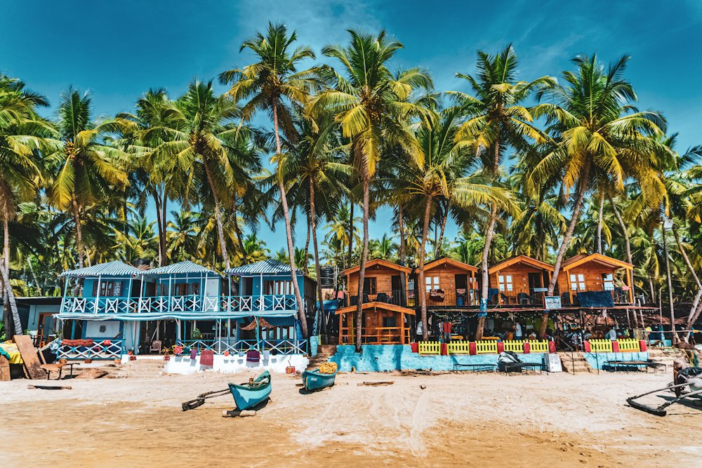 Palm-fringed beach in Goa with colorful beach huts
